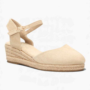 Alpargatas Nuxual de cuña baja en color beige con puntera cerrada, talón abierto y correa ajustable con hebilla.
