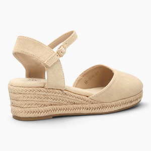 Alpargatas Nuxual de cuña baja en color beige con puntera cerrada, talón abierto y correa ajustable con hebilla.